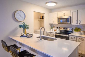 A kitchen with a white countertop and a clock on the wall.